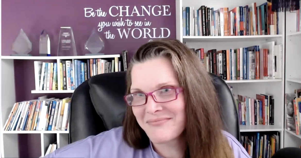 Megan Fuciarelli in her office with bookshelves and a wall quote reading “Be the CHANGE you wish to see in the WORLD.”